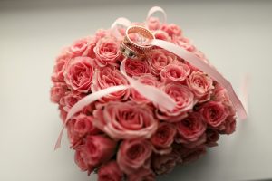 תמונה של סידור פרחים לחתונה עליו מונחות טבעות נישואין